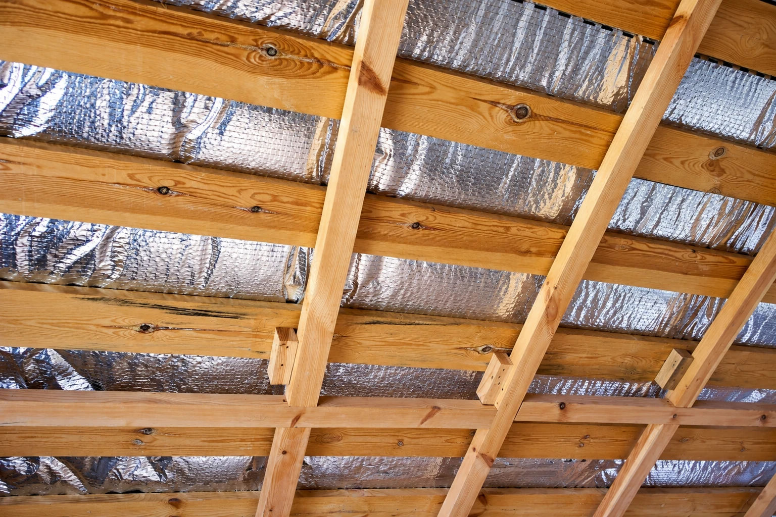 Wooden roof framing lined with reflective foil insulation.